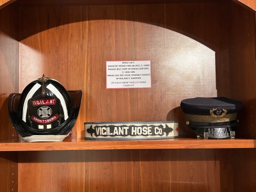 Helmets, hats, and belts on display, loaned from Vigilant Hose Company